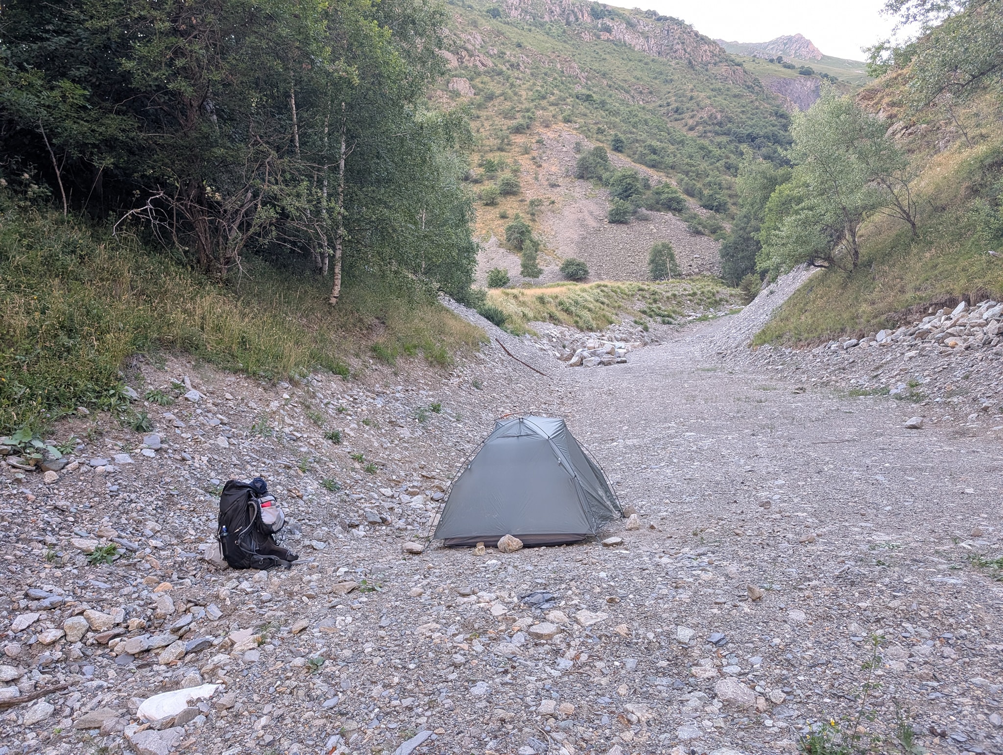 Teltplass på sandfyllingen ved siden av elven.